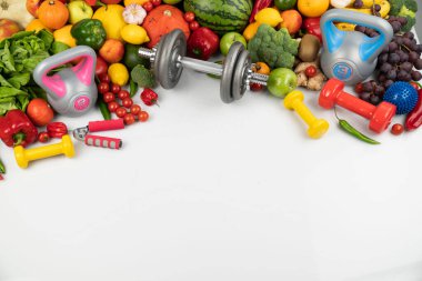 Fitness konsepti. Sağlıklı beslenme: meyve ve sebze. Spor aletleri: tartı makinesi ve dambıllar. Beyaz arkaplan.