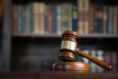 Yargıç ofisi. Gavel kahverengi masada ve kitaplıktaki hukuk kitaplarının koleksiyonu..