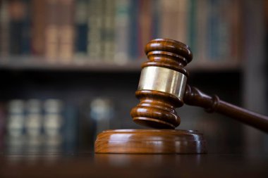 Yargıç ofisi. Gavel kahverengi masada ve kitaplıktaki hukuk kitaplarının koleksiyonu..