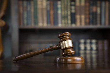 Yargıç ofisi. Gavel kahverengi masada ve kitaplıktaki hukuk kitaplarının koleksiyonu..