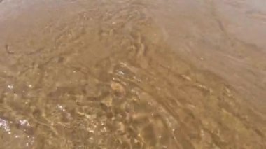 Saf temiz su ve sarı kum. Güneşin parlaklığı. Yakın plan. Güzel doku.