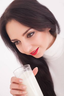 Şirin sağlıklı kadın süt beyaz arka plan üzerinde izole bir bardaktan içiyor.