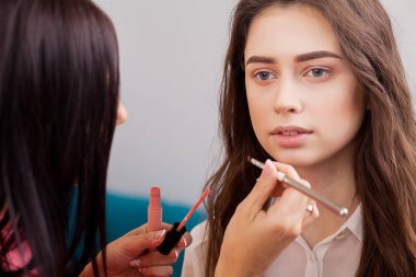 Kalıcı makyaj ana, resim dudaklar genç güzel modeli el. Makyaj devam ediyor