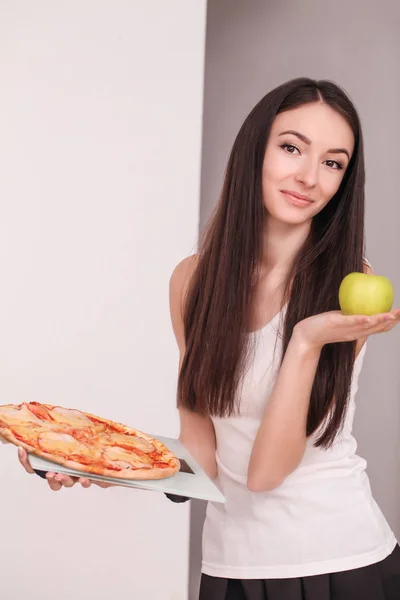 Dieta. Jovem mulher bonita faz uma escolha entre estilo de vida saudável e alimentos nocivos. O conceito de alimentação saudável e obesidade. Menina bela figura esbelta — Fotografia de Stock