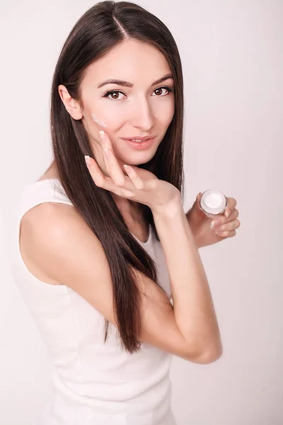 化粧品のクリームを適用します。美しい若い女性適用顔保湿。顔と手のケアの特質 — ストック写真