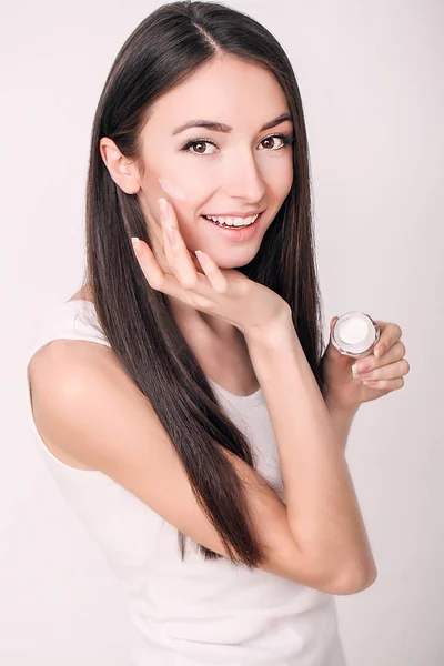 Applicare la crema cosmetica. Una bella giovane donna che applica crema idratante viso. Cura del viso e delle mani — Foto Stock