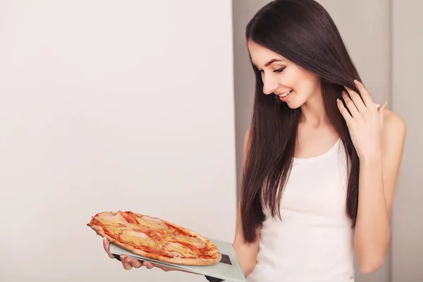 Régime alimentaire. Une jeune femme tenant une pizza sur la balance. Le concept de saine alimentation — Photo