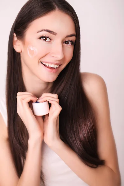 Bellezza, persone, cura della pelle e cosmetici concetto - felice giovane donna con crema idratante a portata di mano e viso — Foto Stock