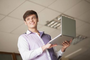 ofiste duran dizüstü kullanan genç iş adamı