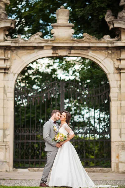 Beau marié câlin belle mariée avec bouquet dans romantique parc européen — Photo