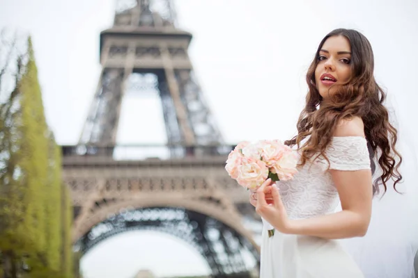 Glückliche Braut mit Blumenstrauß posiert in einem Eiffelturm im Sonnenuntergang — Stockfoto