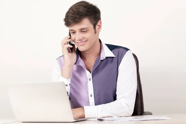 Porträtt av ung affärsman med hjälp av mobiltelefon och bärbar dator medan du sitter på kontoret och arbetar i finansiella rapport. — Stockfoto