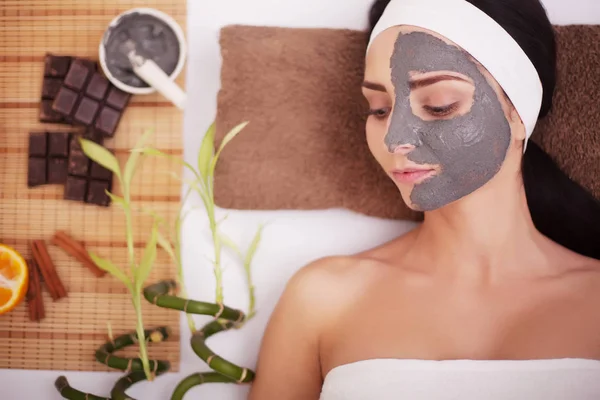 Mujer con máscara facial de arcilla en spa de belleza . — Foto de Stock