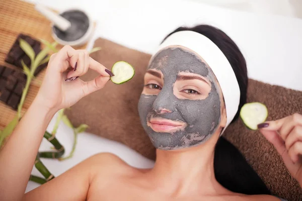 Wanita di salon kecantikan, kesehatan. Prosedur kosmetik wajah wanita dalam masker mitigasi dan irisan mentimun pada mata — Stok Foto