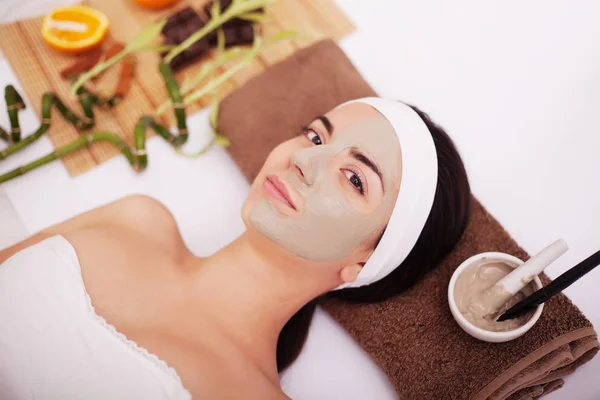 Mujer joven que tiene tratamiento de máscara de piel de arcilla en su cara — Foto de Stock