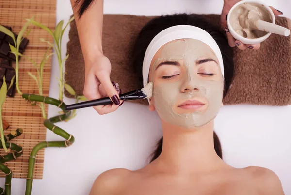 La aplicación de la máscara facial a la cara de la mujer en el salón de belleza — Foto de Stock