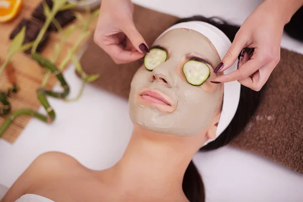 Mujer con máscara facial de arcilla en spa de belleza. En el fondo plantas tropicales — Foto de Stock