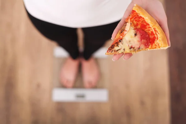 Dieta. Woman Measuring Body Weight On Weighing Scale Holding Pizza (en inglés). Los dulces son comida chatarra malsana. Dieta, Comida Saludable, Estilo de Vida. La pérdida de peso. Obesidad. Vista superior — Foto de Stock