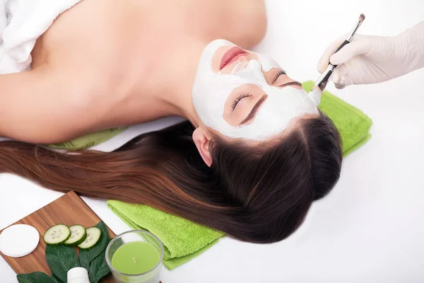 Ung vacker kvinna som får lera ansiktsmask i spa skönhetssalong. Hudvård, skönhetsbehandlingar. — Stockfoto