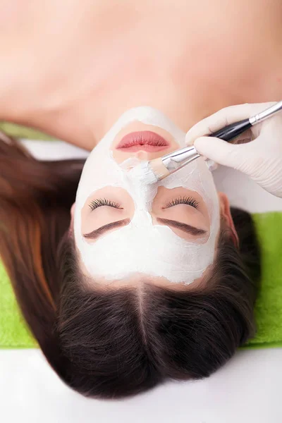 Jovem mulher bonita recebendo máscara facial de barro no salão de beleza spa. Cuidados com a pele, tratamentos de beleza . — Fotografia de Stock