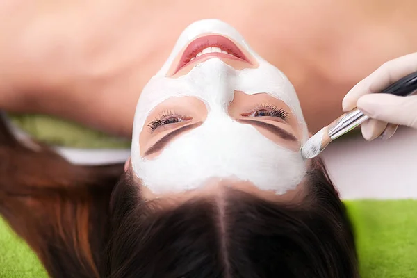 Спа-терапия для молодой женщины, получающей маску для лица в салоне красоты - в помещении — стоковое фото