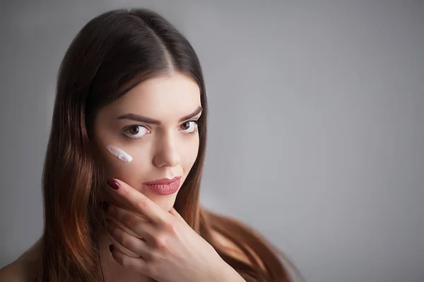 Hermosa modelo aplicando tratamiento de crema cosmética en su cara —  Fotos de Stock