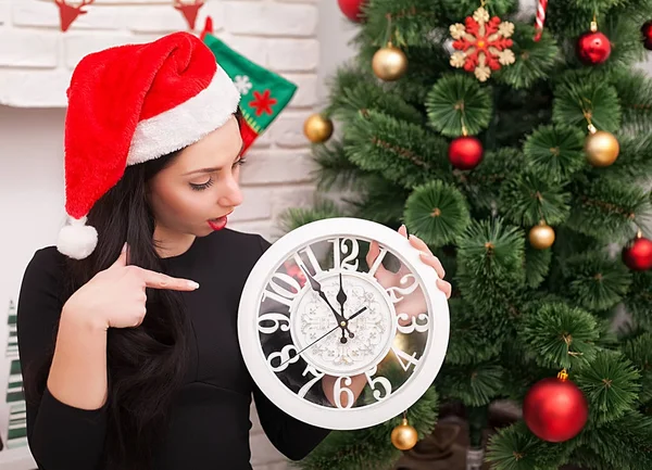 Schattig meisje in santa hoed met versierde kerstboom en oude klok — Stockfoto
