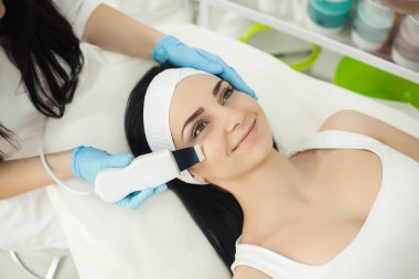 Woman receiving electric facial peeling at european beauty salon. clipart