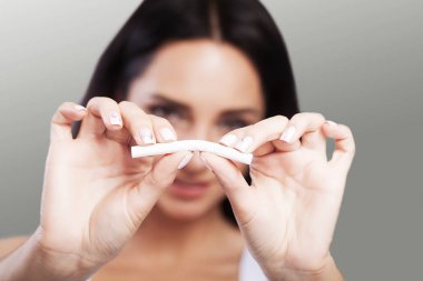 Sigarayı bırakmak. Closeup sigara elinde tutan, yarım parmak ile kırılma güzel gülümseyen kadın portresi. Sigara sigara kavramı çıkın.