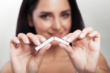 Quit Smoking. Closeup Of A Beautiful Happy Woman Breaking A Cigarette. Portrait Of A Smiling Woman Holding A Broken Cigarette In Hands. Healthy Lifestyle Concept.
