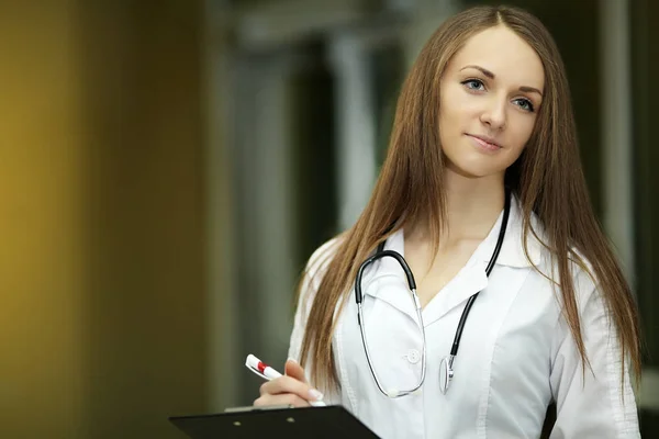Smiling family doctor with a stethoscope. Healthcare. Young woman. Graduate student. In a medical institution. White robe. — Stock Photo, Image