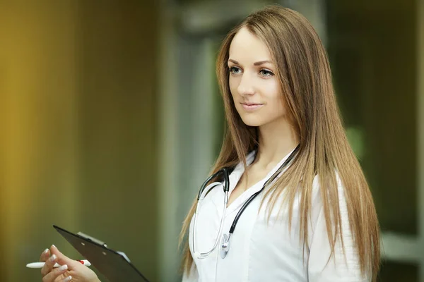 Medicine. Portrait of a smiling young nurse with a blurred patient in the hospital corridor. Cool clothes. Doctor. Family doctor. — Stock Photo, Image