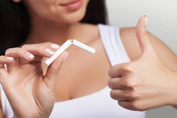 Pára de fumar. Retrato de perto da bela mulher sorridente segurando cigarro nas mãos, quebrando-o ao meio com os dedos. Parar de fumar cigarro conceito . — Fotografia de Stock