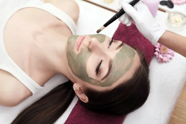Terapia de spa para mulher jovem recebendo máscara facial no salão de beleza — Fotografia de Stock