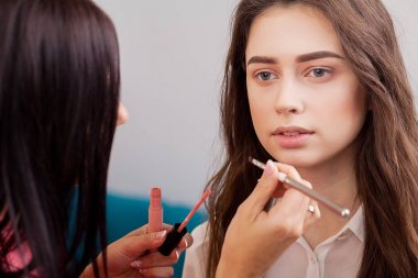 Kalıcı makyaj ana, resim dudaklar genç güzel modeli el. Makyaj devam ediyor