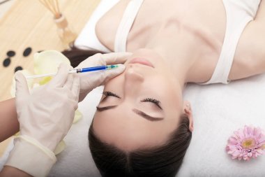 Genç kadın enjeksiyon alnı alıyor. O doktor ofisinde oturuyor ve rahatlatıcı