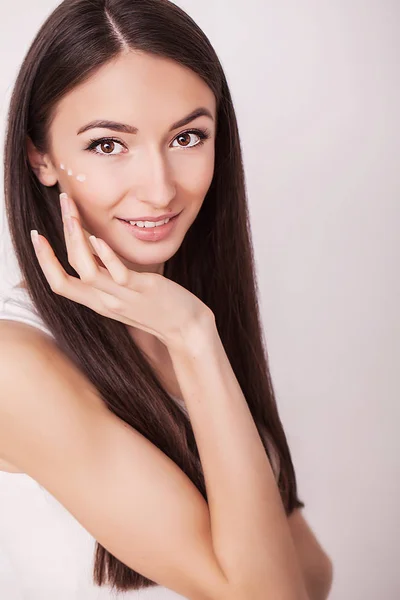 Schönheit, Menschen, Hautpflege und Kosmetikkonzept - glückliche junge Frau mit feuchtigkeitsspendender Creme auf Hand und Gesicht — Stockfoto