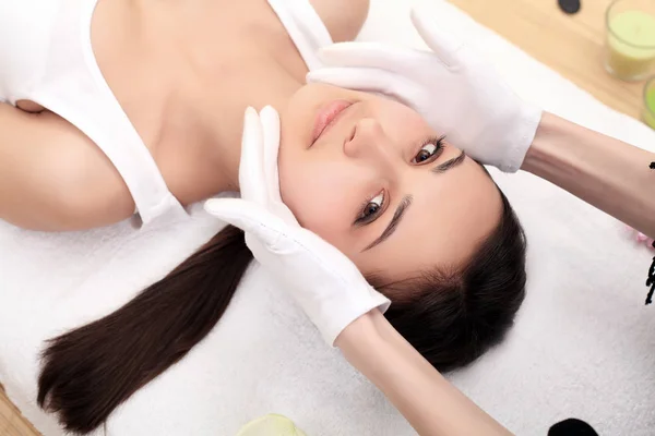 Расслабляющая красивая женщина с массажем для ее кожи на лице в салоне красоты - горизонтальный — стоковое фото