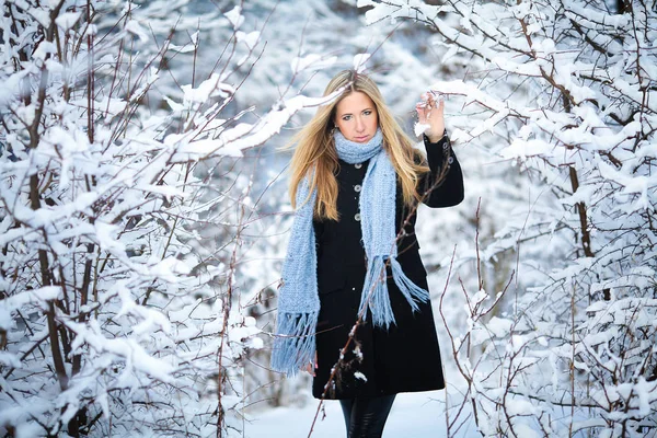 Menina loira jovem atraente andando na floresta de inverno. Mulher bonita no inverno ao ar livre. Vestindo roupas de inverno . — Fotografia de Stock