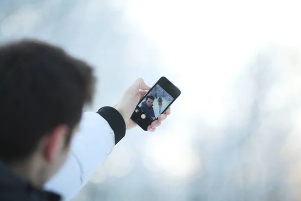 Un jeune homme fait la photo au téléphone pendant une séance photo d'hiver. Selfies . — Photo