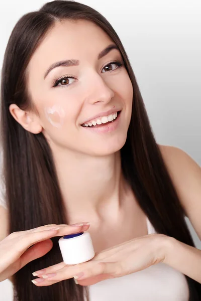Bella giovane donna che applica la crema viso al suo osso della guancia in un — Foto Stock
