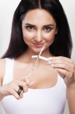 Sigara içmek yasak. Kız sigara makas ile keser. Sağlık kavramı sigara karşı. Gri bir arka plan üzerinde.