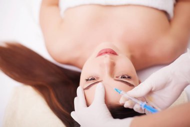 Kozmetik uzmanının elleri yüzüne ve dudaklarına iğne yapıyor. Genç bir kadın güzellik salonunda yüz aşısı yaptırıyor. Yaşlanma, gençleşme ve hidrasyon prosedürleriyle yüzleş. Estetik kozmetoloji. Kapat..