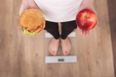 Elma ve hamburger arasında seçim yapma kadın görünümünü kapat