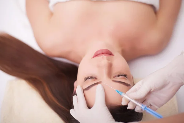 Manos del cosmetólogo haciendo inyección en la cara, labios. Mujer joven recibe inyecciones faciales de belleza en el salón. Procedimientos de envejecimiento facial, rejuvenecimiento e hidratación. Cosmetología estética. De cerca.. — Foto de Stock