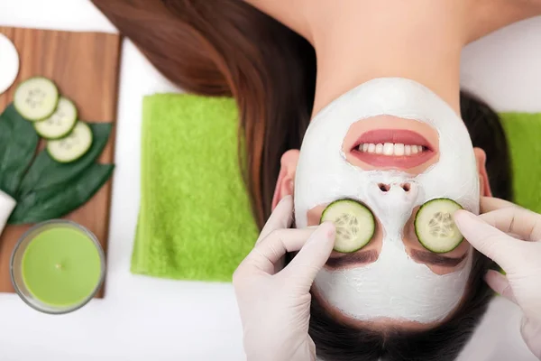 Beautiful woman having clay facial mask apply by beautician. — Stock Photo, Image