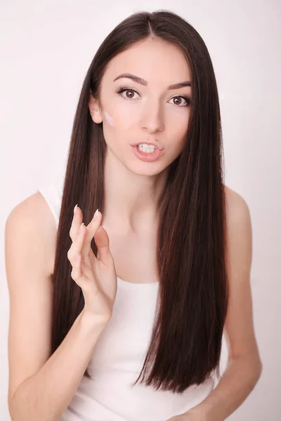 Attractive girl putting anti-aging cream on her face — Stock Photo, Image