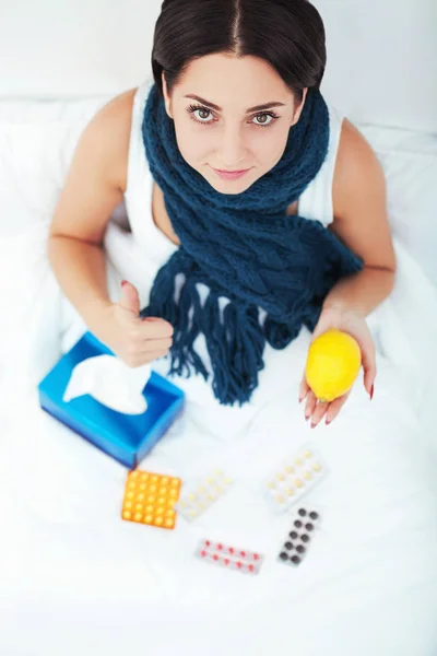 Mladá žena leží na posteli a drží medicína puchýř pilulky — Stock fotografie