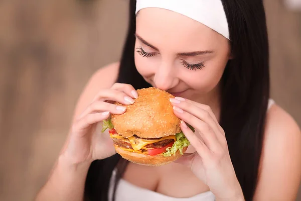 O tânără dintr-un restaurant bun mănâncă un hamburger, se comportă necorespunzător — Fotografie, imagine de stoc
