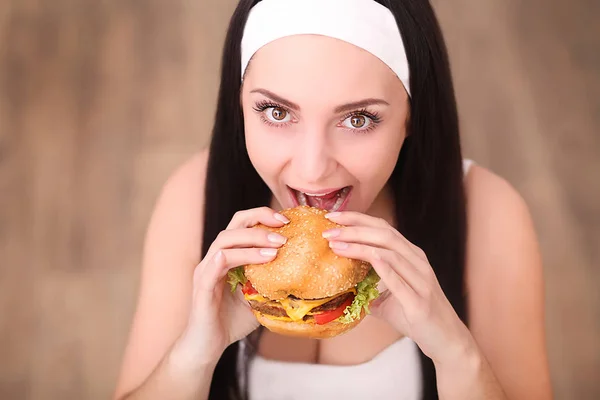 Joven mujer en un restaurante de alta cocina comer una hamburguesa, se comporta mal — Foto de Stock